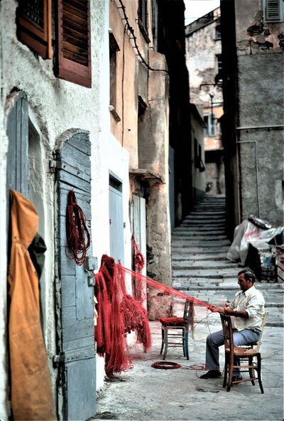 Hombre reparando una red de pesca en Córcega